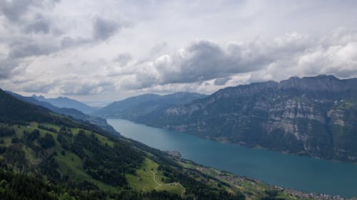 Aerial Photography of Lake between Mountains under the Cloudy Sky