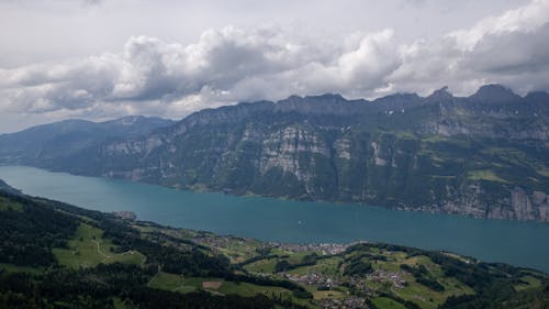 Aerial Photography of Lake between Mountains under the Cloudy Sky