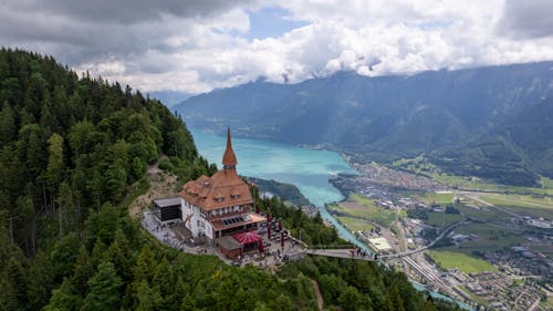 Brown and White Concrete Building Near Green Trees and Body of Water