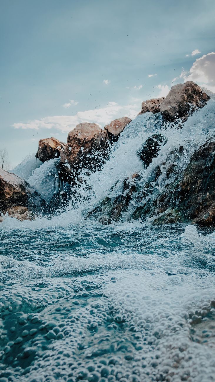 Captivating view of waves crashing against the rocky shoreline in Adıyaman, Turkey, under a blue sky.