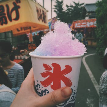 Vibrant shaved ice dessert held at a bustling Japanese street festival, capturing cultural flavor.