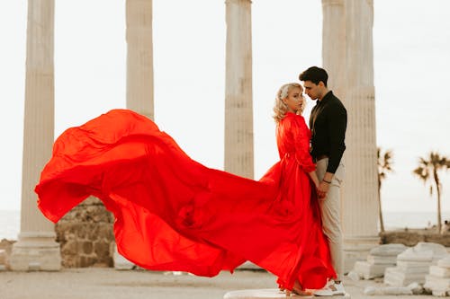 A Man Holding Hands with a Woman in a Red Gown