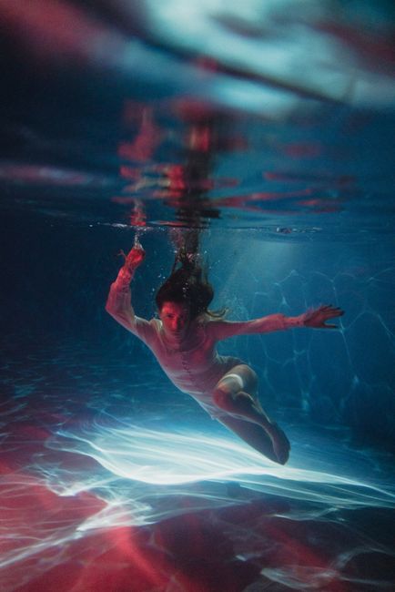 Artistic photo of a woman swimming underwater with flowing hair and serene expression.