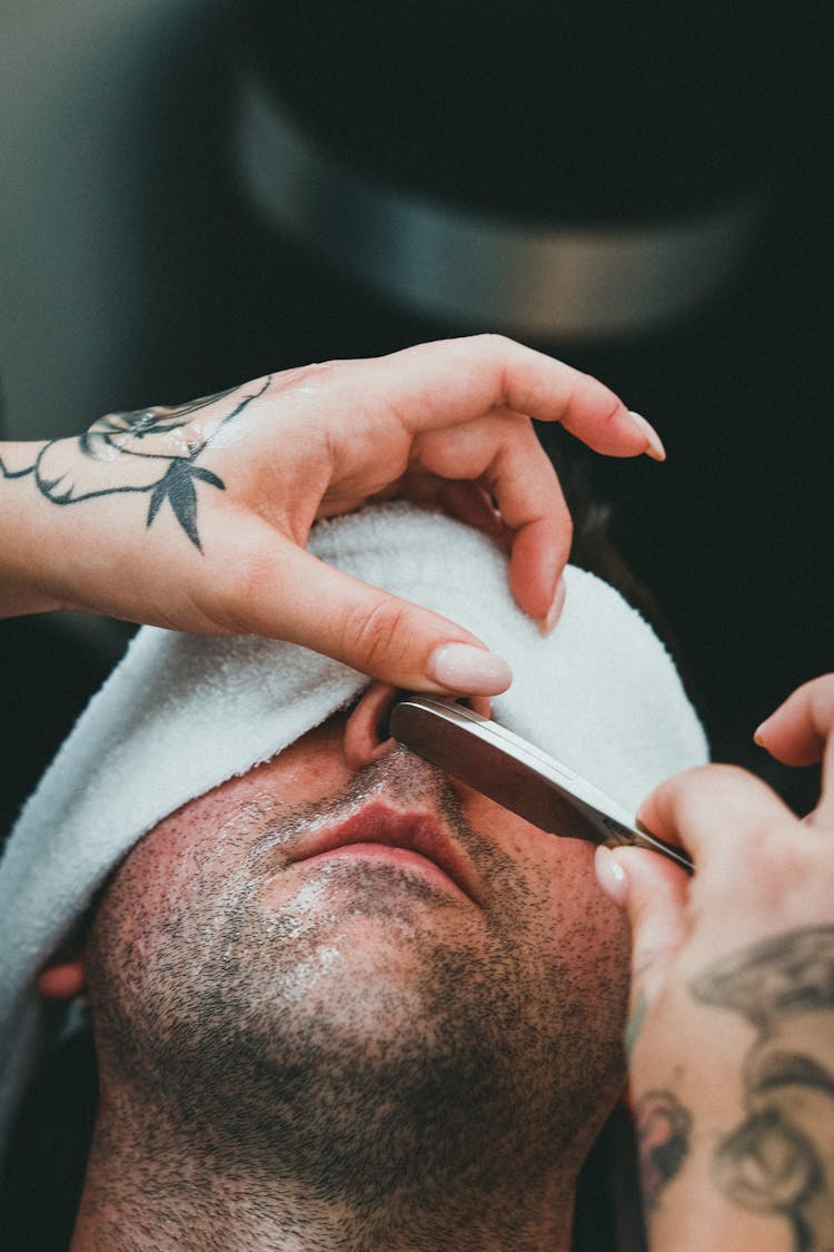 Man In Beauty Spa Receiving Face Care From Woman