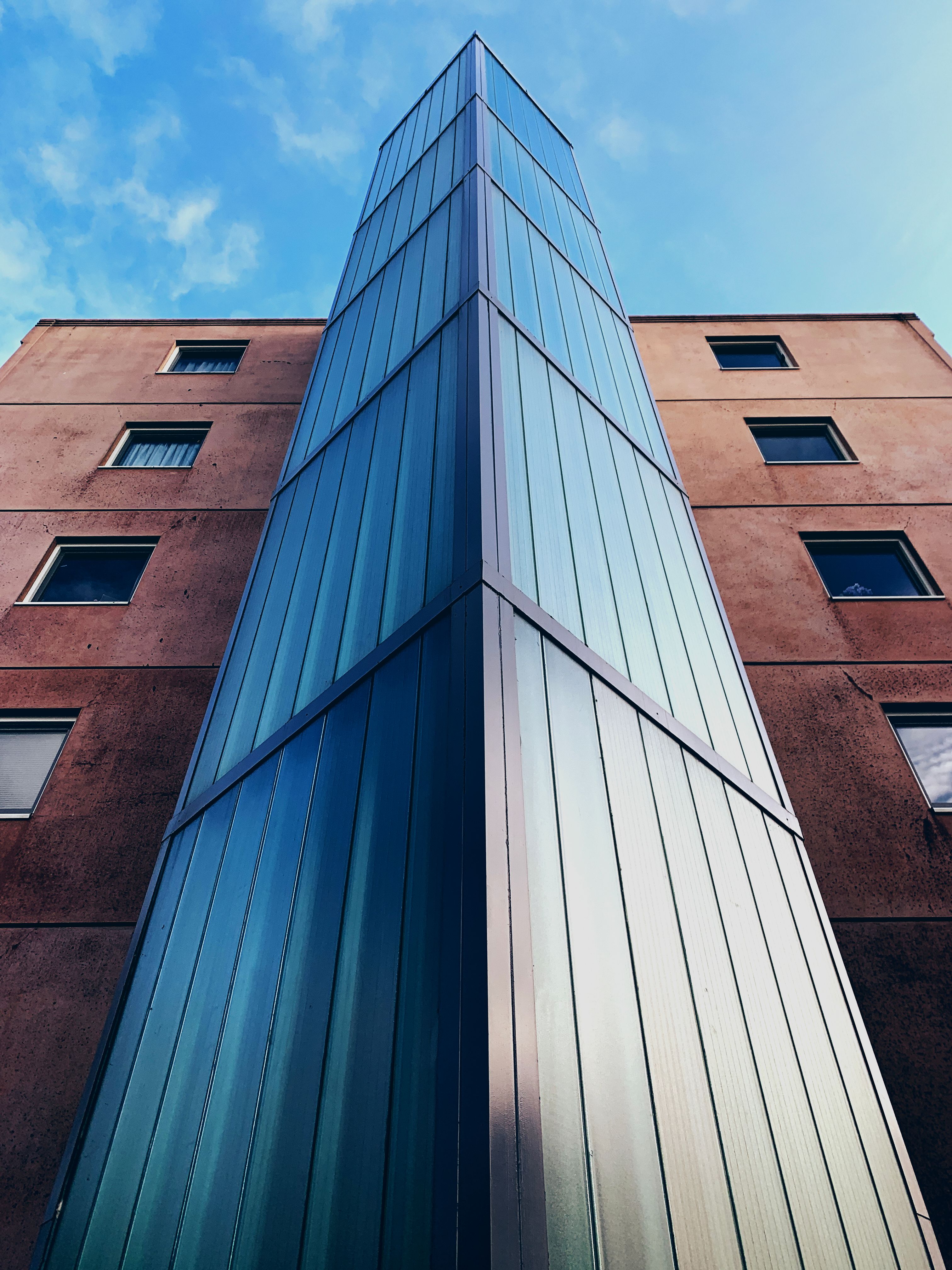 A Glass Building Beside a Brown Concrete Building · Free Stock Photo