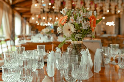 Free A beautiful bouquet centerpiece with glassware on a wooden table inside a rustic restaurant. Stock Photo