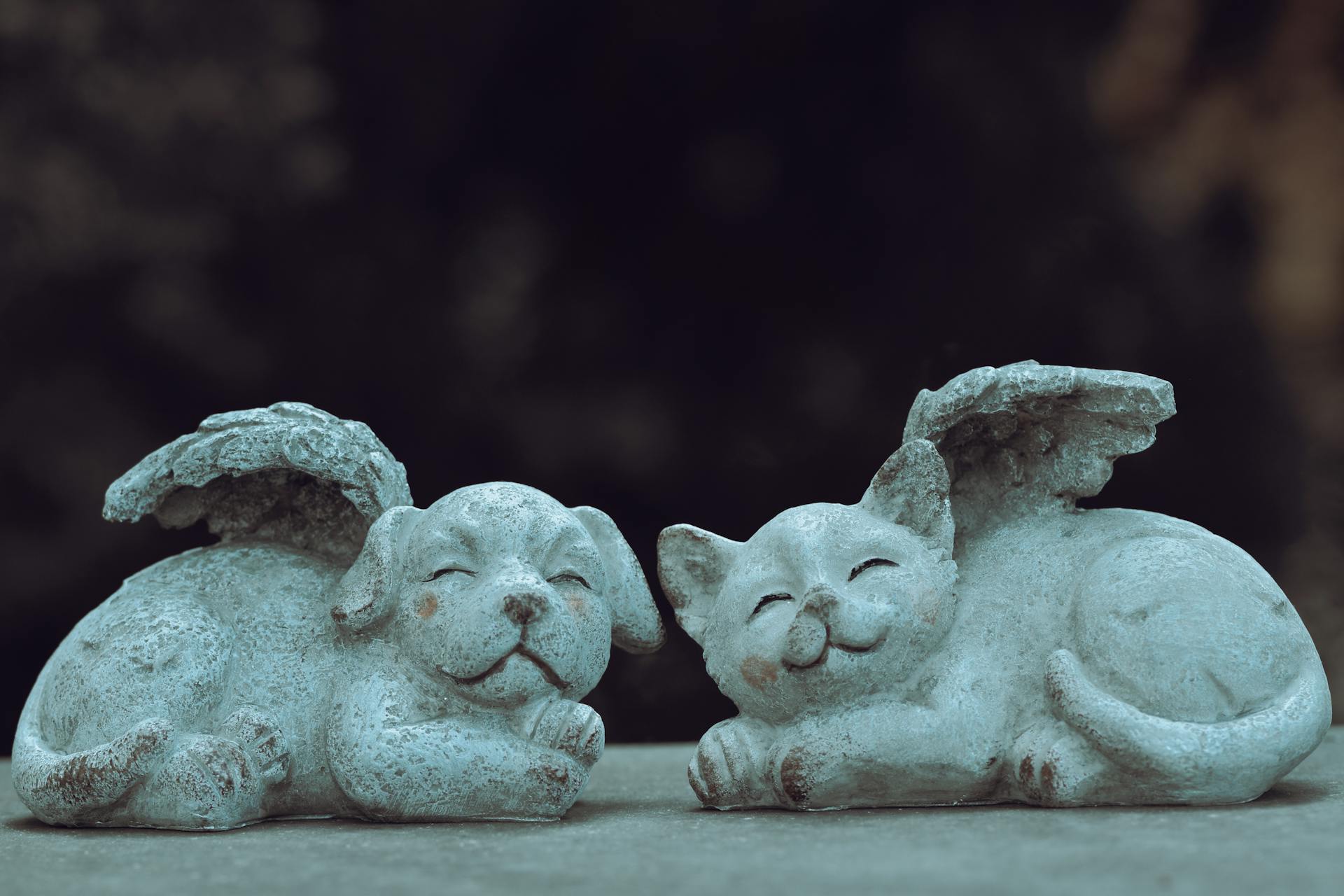 A Gray Ceramic Figurine of a Dog and Cat with Tiny Wings