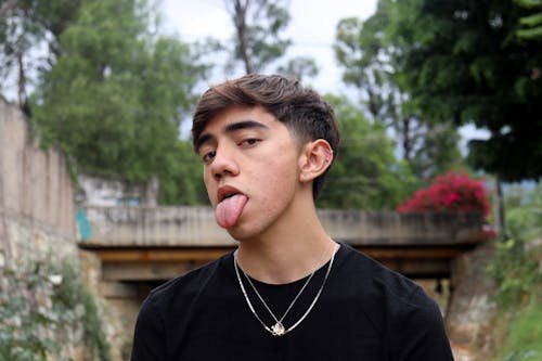 A Man in a Black Shirt Wearing Earrings and Necklaces