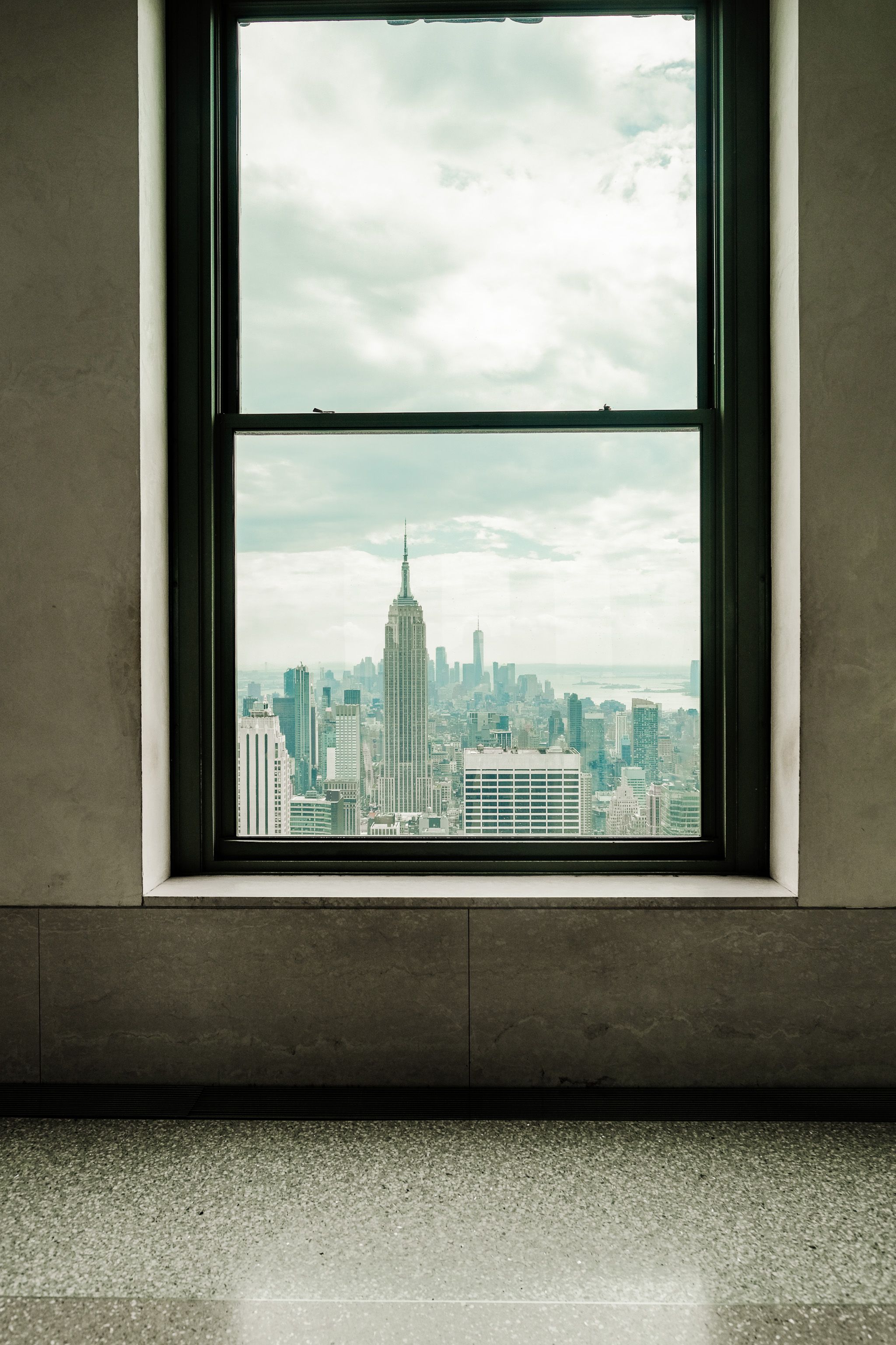 Empire State Building view from a window in New York City, offering a classic skyline perspective.
