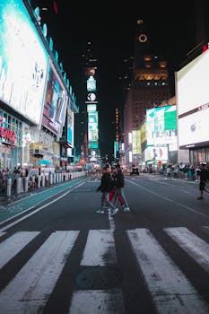 A bustling night scene of Times Square with vibrant lights and people crossing the street.