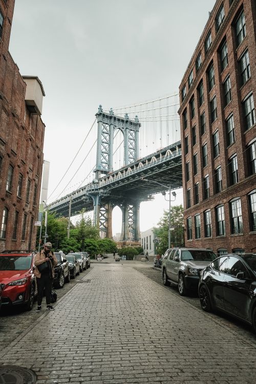 Free Street view of the Manhattan Bridge framed by red brick buildings in Brooklyn, New York City. Stock Photo