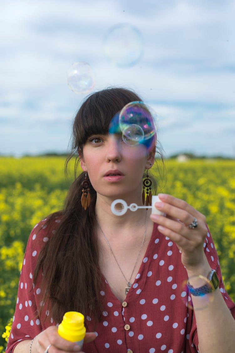 Girl In Red And White Polka Dot Top Blowing Bubbles