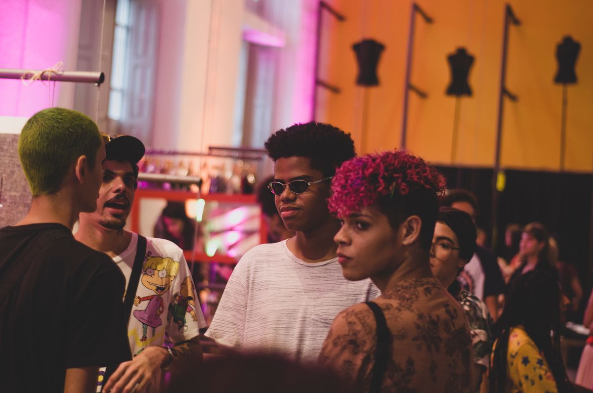 A stylish group of young adults socializing at an indoor fashion event