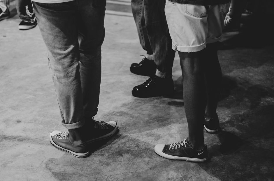 Black and white photo capturing a casual gathering, emphasizing footwear styles.