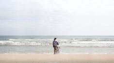 Man in Gray Jacket Walking on Beach