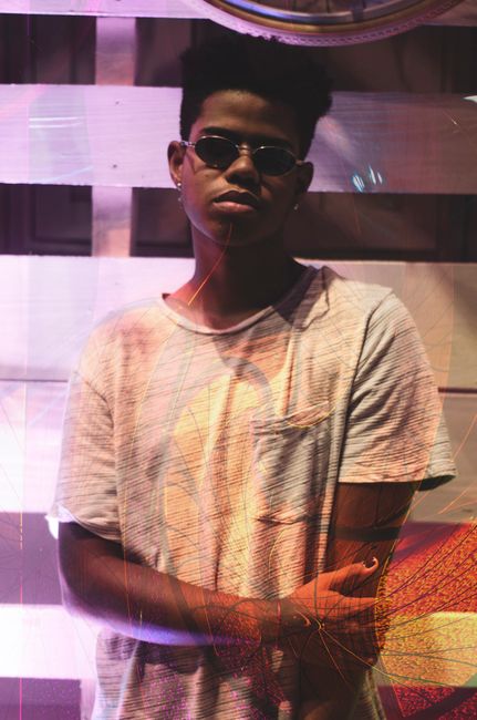 Fashionable young man posing with sunglasses and casual attire, exuding a cool and modern vibe.