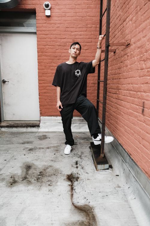 Free A stylish young man stands on a rooftop, leaning against a ladder with urban vibes. Stock Photo