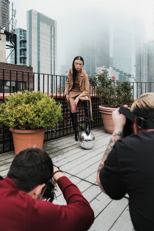 Free High fashion photoshoot featuring a model on a city rooftop, surrounded by skyscrapers. Stock Photo