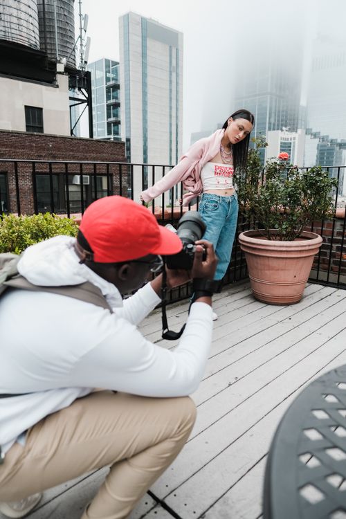 Free Photographer capturing a model posing on a city rooftop terrace during the day. Stock Photo