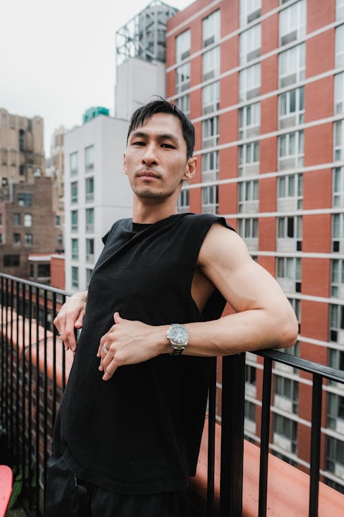 Man in Black Muscle Shirt Leaning on Black Metal Railing