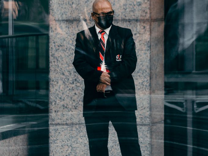 Close protection officer in a dark suit waiting outside a building