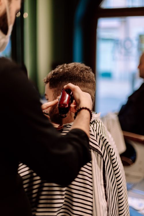 Free Barber giving a stylish haircut in a Geneva shop, captured in a close-up vertical shot. Stock Photo