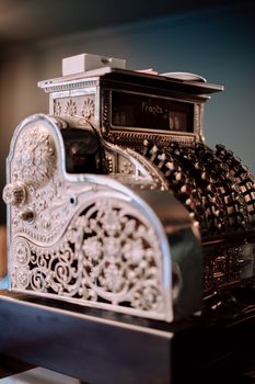 A close-up of an intricate antique cash register with ornate details in a Geneva shop.
