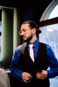 Bearded man in a stylish vest and tie indoors, showcasing modern fashion in Geneva.