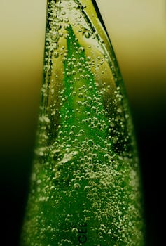 Macro shot of a green aloe vera gel bottle with visible bubbles, emphasizing freshness.