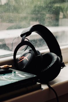 Black headphones resting on a window sill with a book beside them, creating a cozy ambiance.