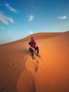 Man in Black and White Shirt and Black Pants Jumping on Brown Sand