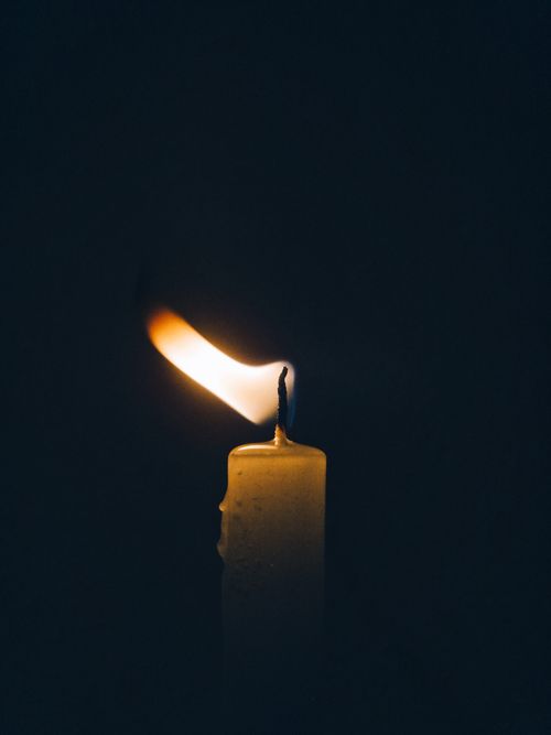 Free Close-up of a candle burning brightly against a dark background, providing warm light and copy space. Stock Photo