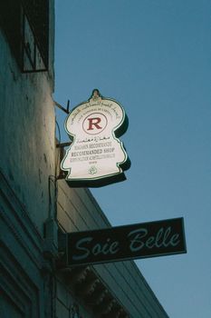 A low angle view of an illuminated shop sign on a building at dusk.
