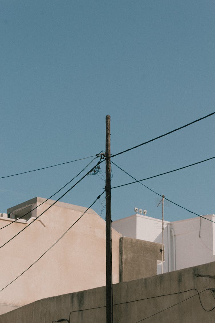 Utility Pole Connecting Wires Over White Buildings 