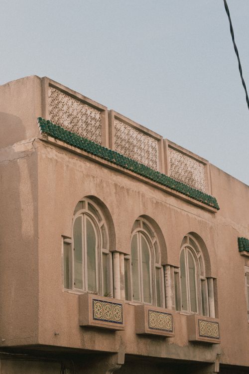 Free Close-up of a building's ornate facade featuring arched windows and traditional tilework under a clear blue sky. Stock Photo