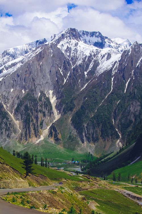 Free Majestic mountains with snow capped peaks and vibrant green valleys under a cloudy sky. Stock Photo