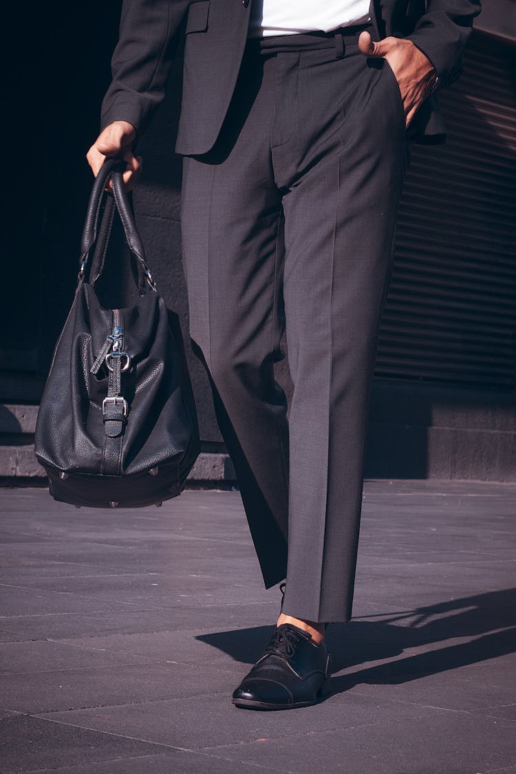 A Person Wearing Black Pants Carrying A Duffle Bag