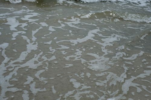 Free Close-up view of gentle ocean waves creating patterns in the sand, perfect for beach and nature themes. Stock Photo
