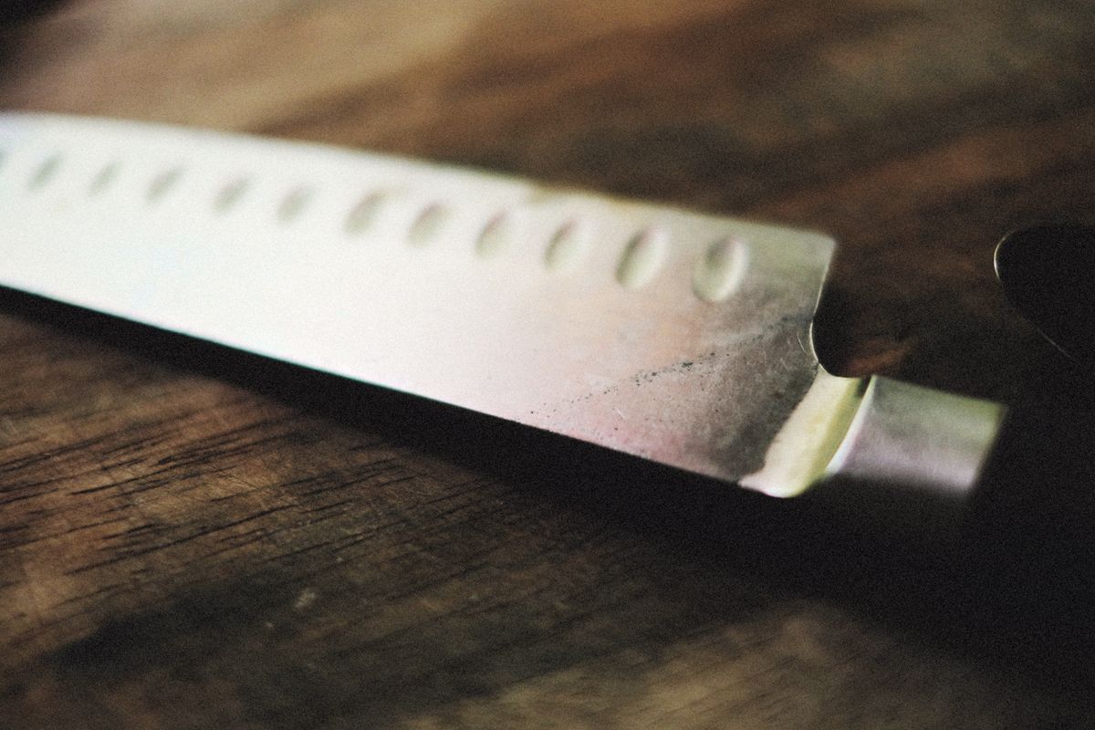 A properly sharpened kitchen knife edge Close-up of a sharp kitchen knife on a wooden surface