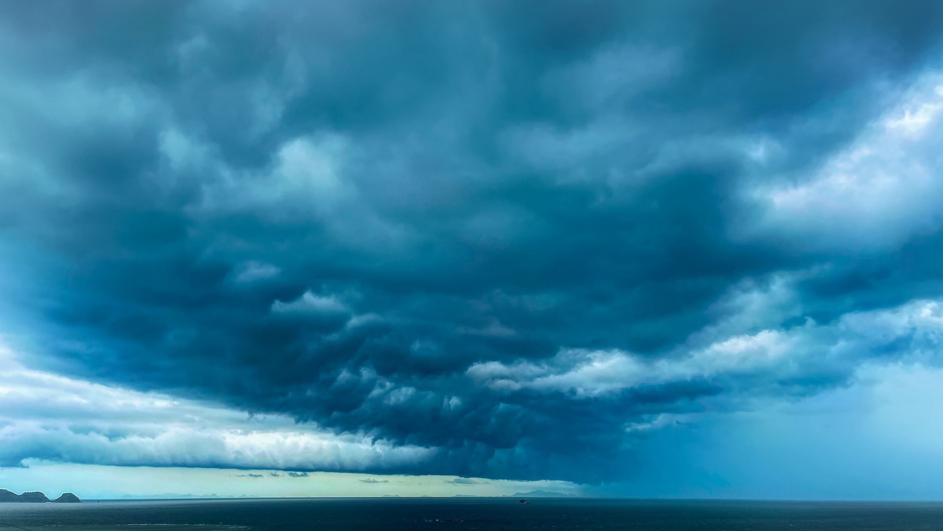 A dramatic formation of dark storm clouds hovering over a vast ocean expanse.
