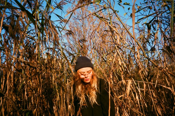 Woman standing in a sunlit field of tall grass — photo by Aleksandr Neplokhov on Pexels