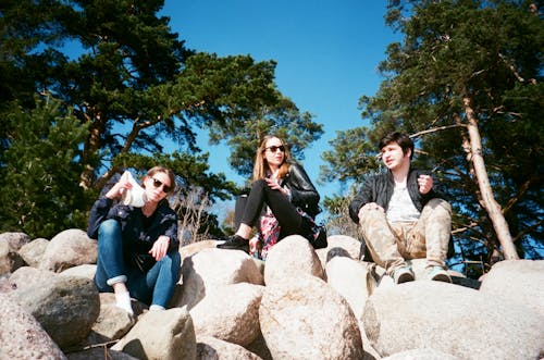 Three Person Sitting on Rock Formation