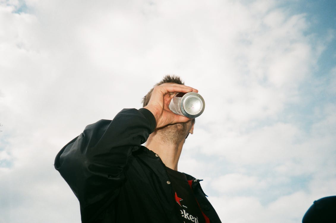 Photographie En Contre Plongée D'un Homme Buvant Une Boîte étiquetée Grise