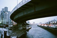 积雪的运河上，一座混凝土桥拱立在繁华的冬季城市景观中