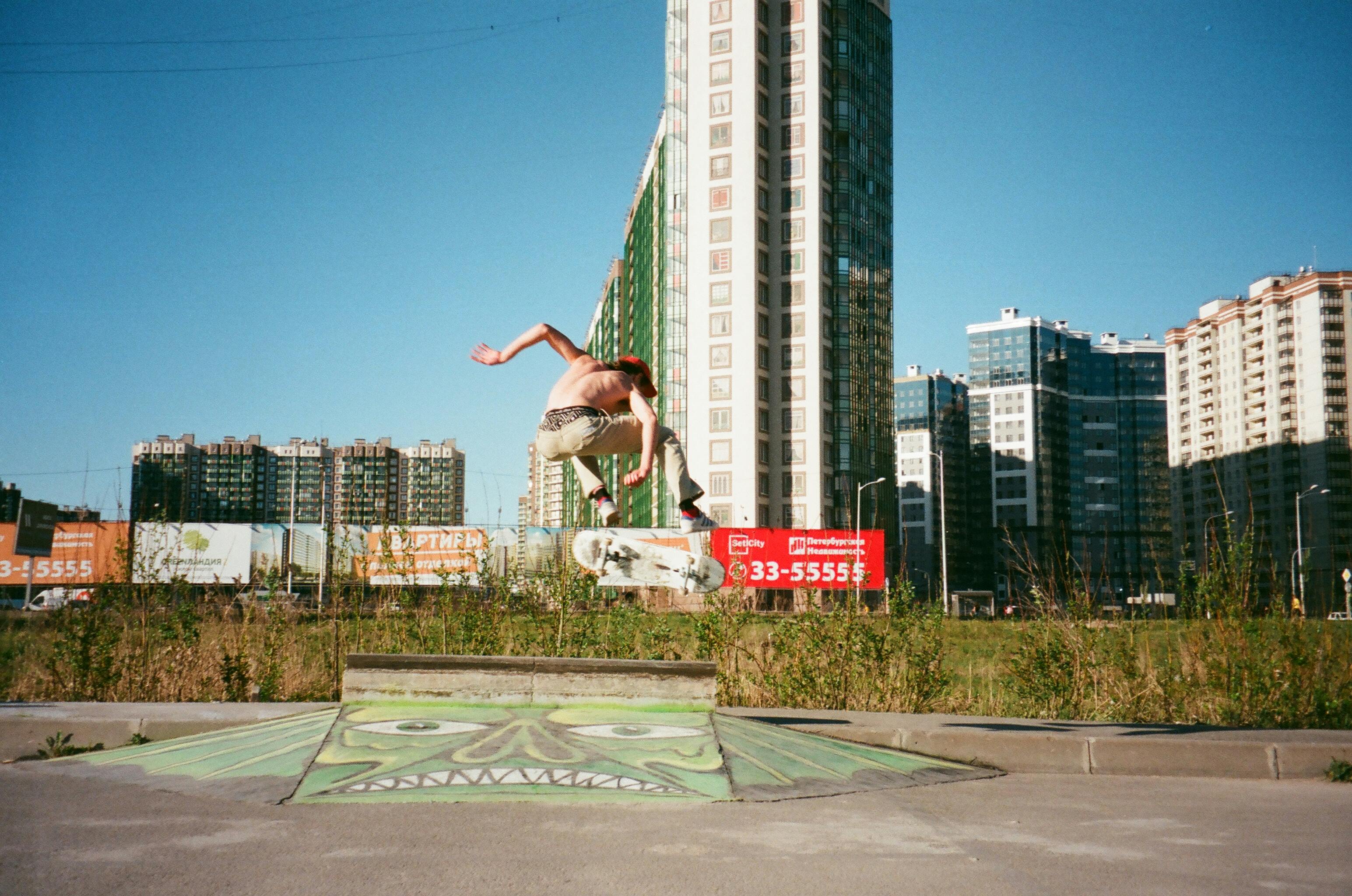 在城市公园的天际线下，滑板运动员表演着特技