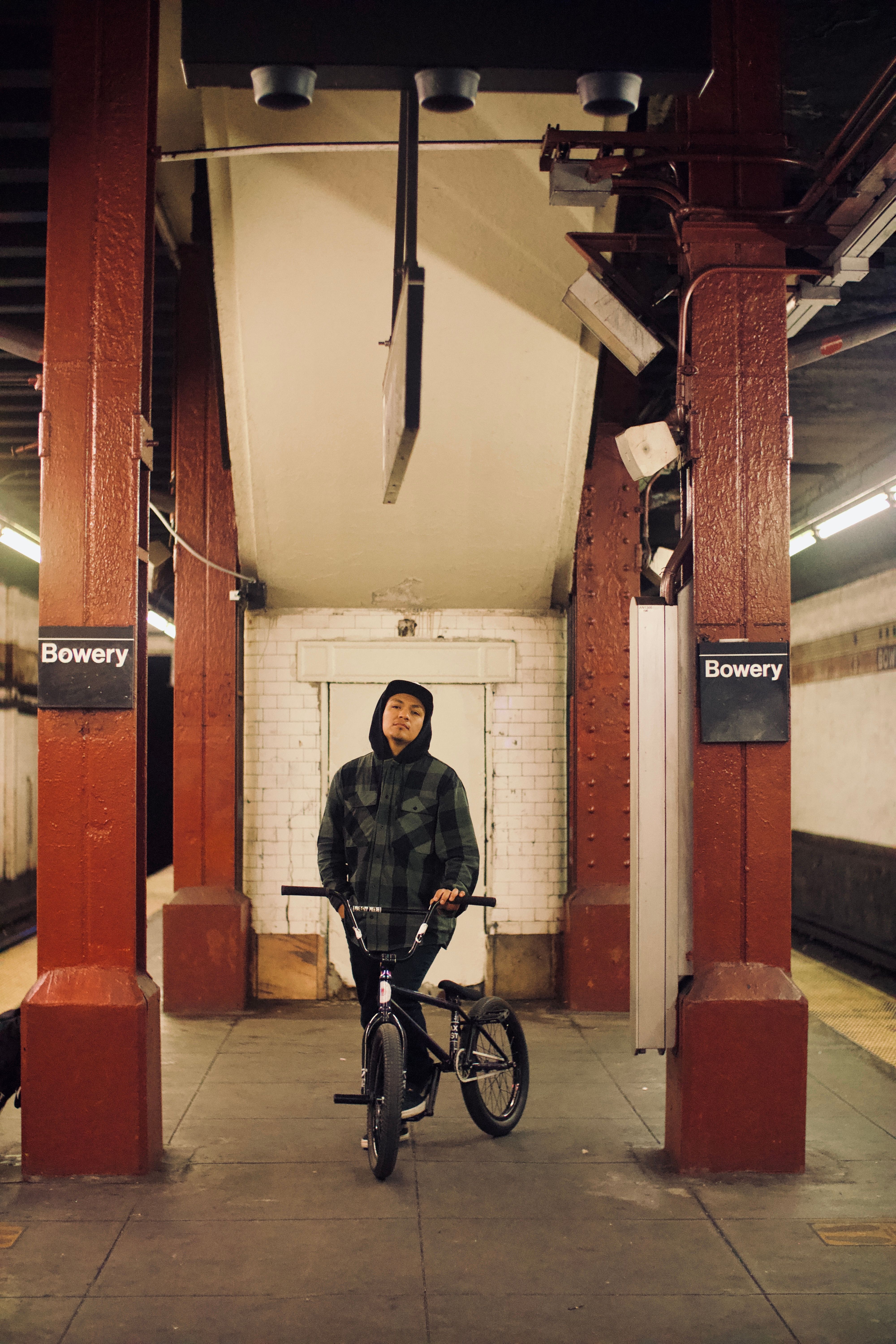 Man with BMX bike at Bowery Station in NYC subway, capturing urban street style.