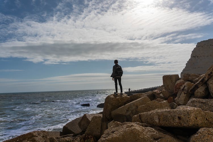 Person Standing On Rock In Front Of Sea