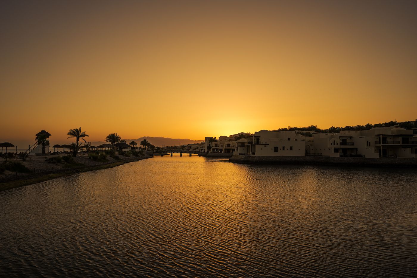 Goldener Sonnenuntergang über einem Resort und ruhigem Wasser