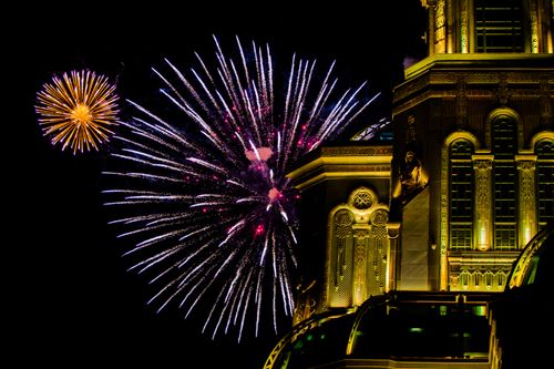 Free Vibrant fireworks display over a beautifully lit building at night. Celebration and excitement captured in one frame. Stock Photo