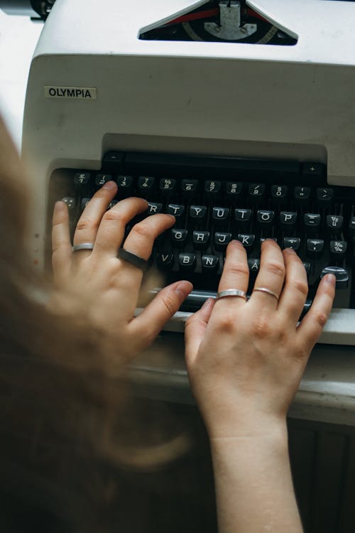 A Person's Hand on Black Typewriter